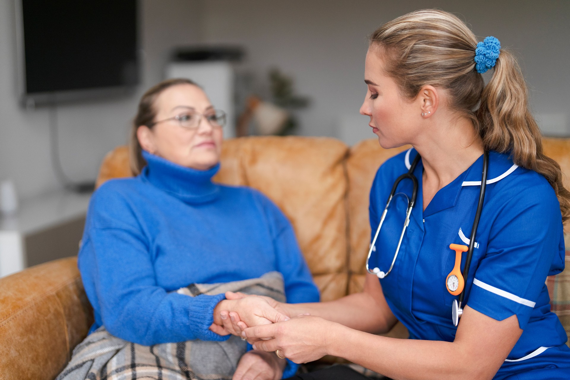 Healthcare professional provides compassionate support to elderly patient in cozy living room setting during afternoon visit